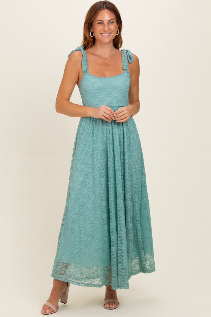 woman wearing a teal lace maxi dress with tie shoulder straps and a flowing skirt