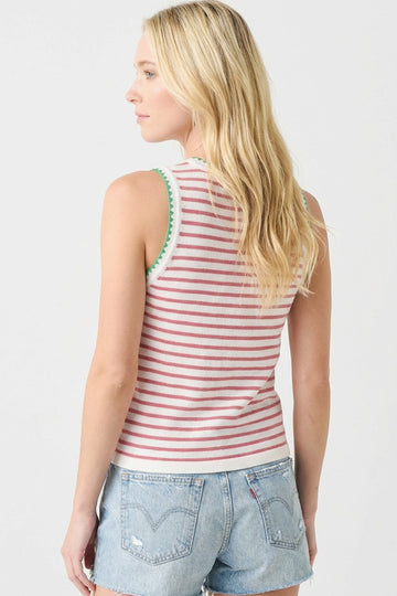 woman wearing a red and white striped sleeveless top with green trim, paired with denim shorts