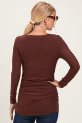 woman wearing a brown long sleeve top with gathered detailing at the back, styled with jeans and sunglasses