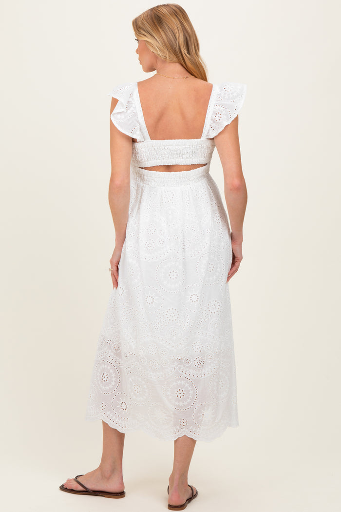 woman wearing a white maternity dress with ruffled sleeves and a back cutout, featuring intricate eyelet details