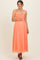 woman wearing a coral maternity maxi dress with adjustable straps, smocked bodice, and holding her baby bump