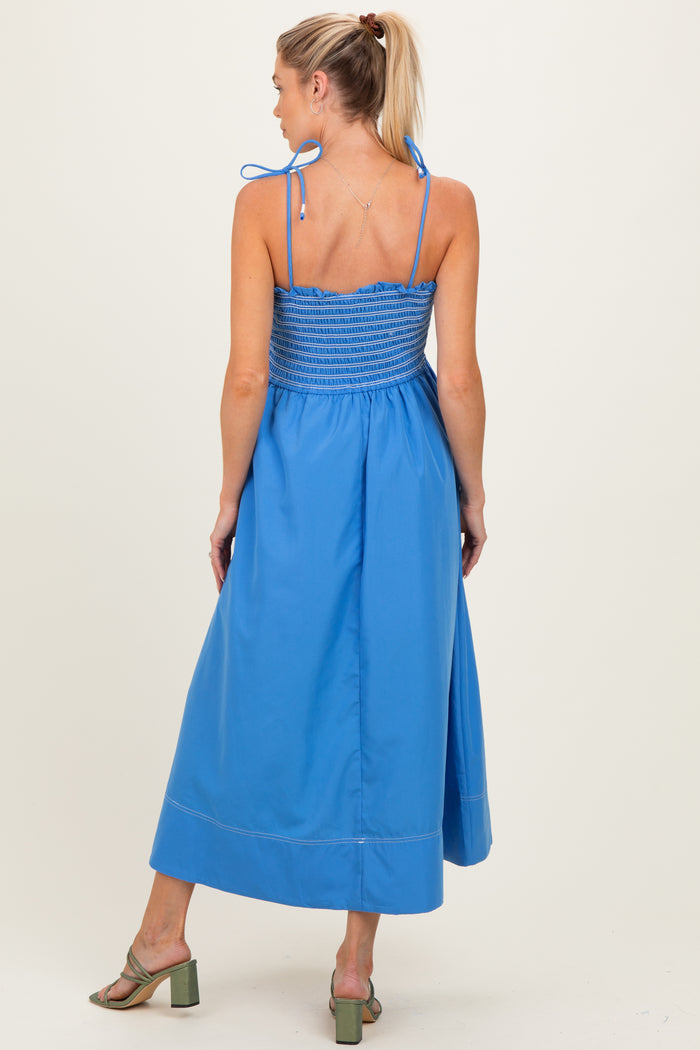 woman wearing a blue maternity maxi dress with adjustable straps and smocked bodice, viewed from the back