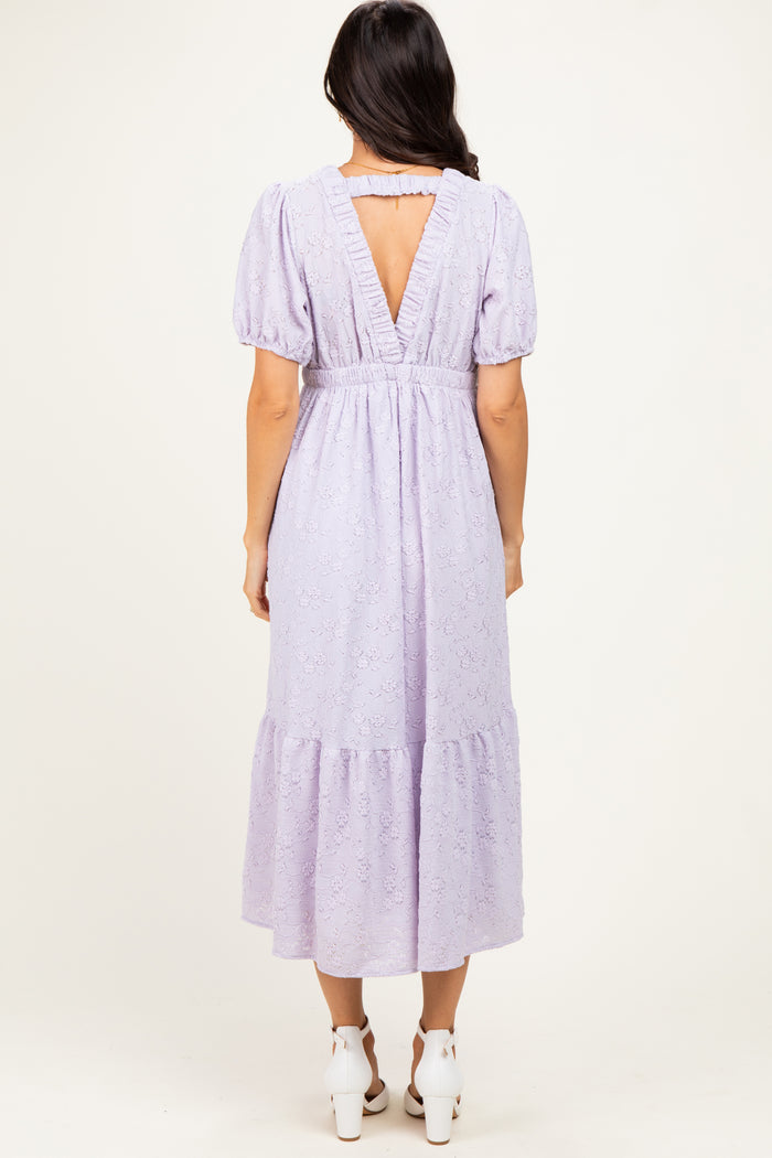 woman wearing a lavender puff sleeve midi dress with a tiered hem and a v-back detail