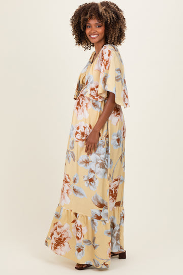 woman wearing a floral yellow maxi dress with flutter sleeves and a visible baby bump