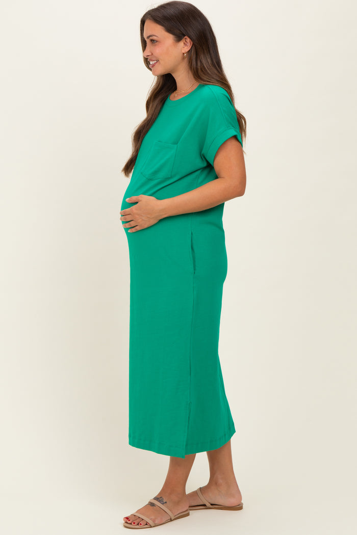 woman wearing a green short sleeve maternity maxi dress and cradling her baby bump