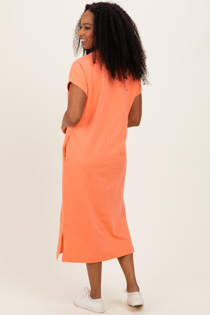 woman wearing an orange short sleeve midi dress with side slits, standing with her back to the camera