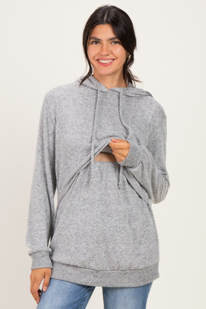 woman wearing a gray hoodie with a cut-out detail and long sleeves, smiling at the camera