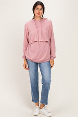 woman wearing a pink cropped hoodie with drawstrings, paired with blue jeans and white sneakers