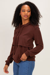 woman wearing a brown hooded sweatshirt with layered design and long sleeves, styled with blue jeans
