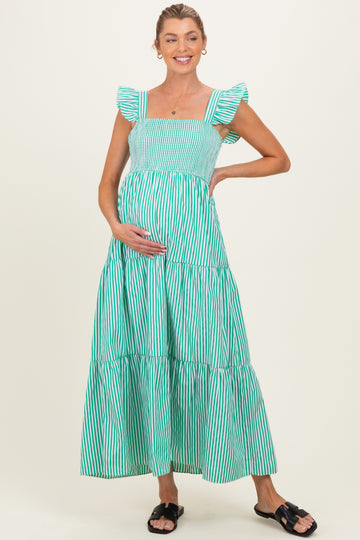 woman wearing a green and white striped maternity maxi dress with ruffle sleeves and holding her baby bump