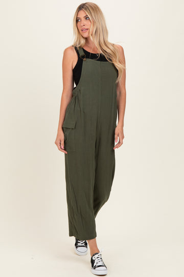 woman wearing an olive green jumpsuit with adjustable straps and side pockets, paired with black sneakers