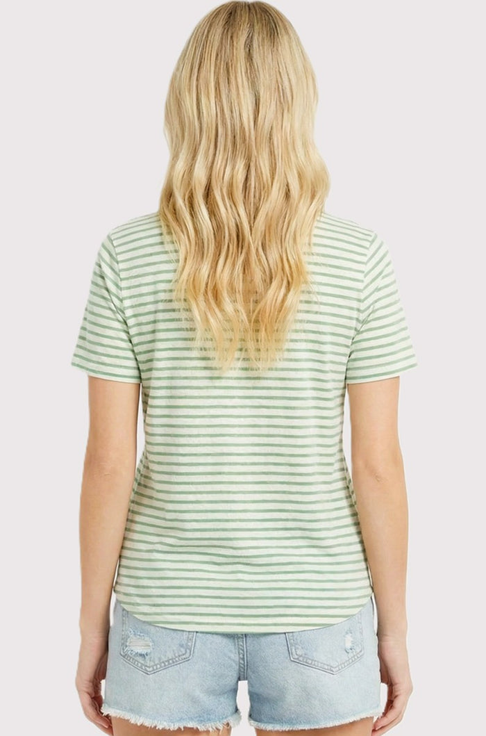 woman wearing a green and white striped short sleeve top with a relaxed fit and light blue denim shorts.