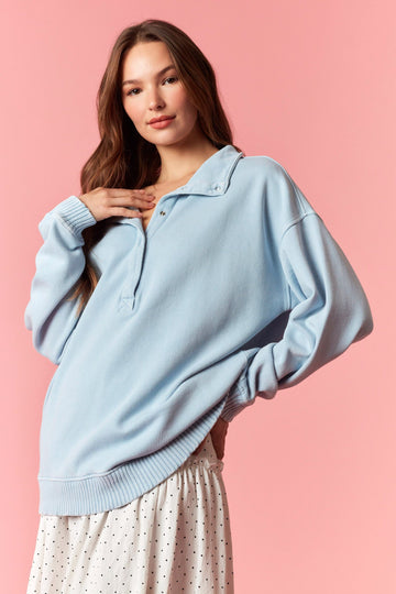 woman wearing a light blue oversized pullover sweatshirt with a collar and paired with a white polka dot skirt