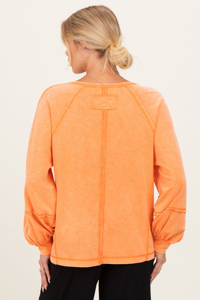 maternity wear in a vibrant orange long sleeve top with puffed sleeves and stitched detailing, view from the back