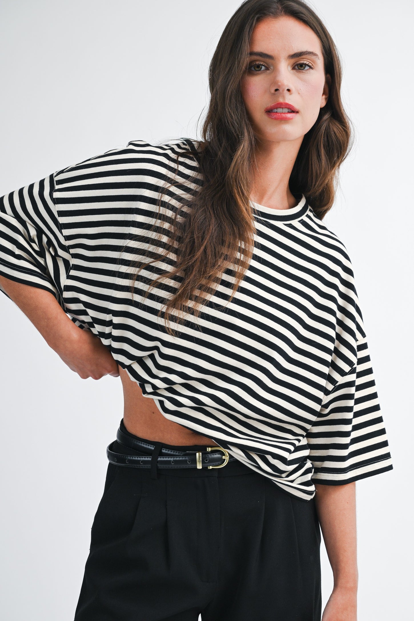 woman wearing a black and white striped oversized t-shirt with wide sleeves and high-waisted black trousers