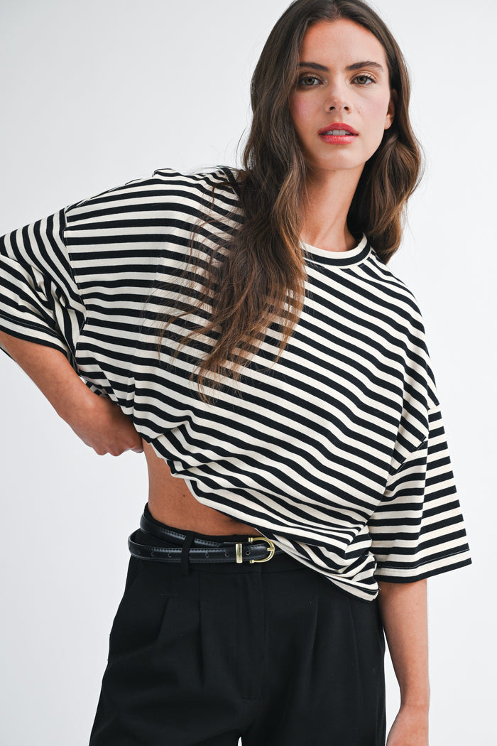 woman wearing a black and white striped oversized t-shirt with wide sleeves and high-waisted black trousers