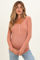 woman wearing a peach long sleeve maternity top with buttons and a visible baby bump