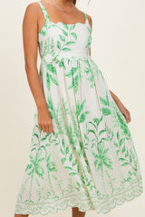woman wearing a white floral maxi dress with green plant prints and scalloped straps