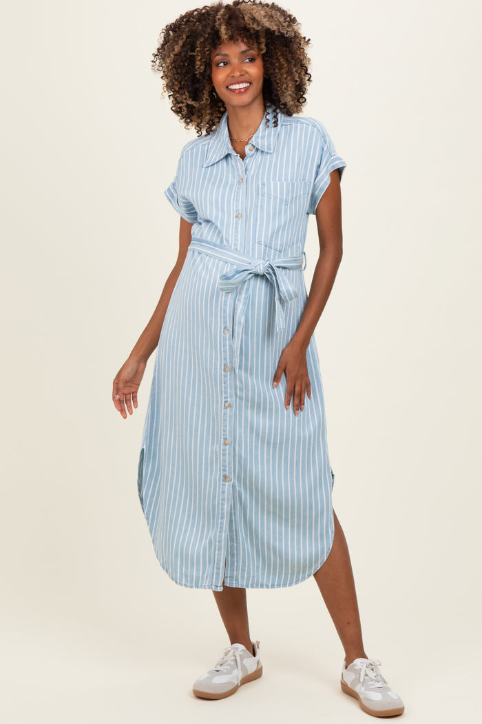 woman wearing a light blue striped maternity dress with a tie belt and short sleeves, standing and smiling