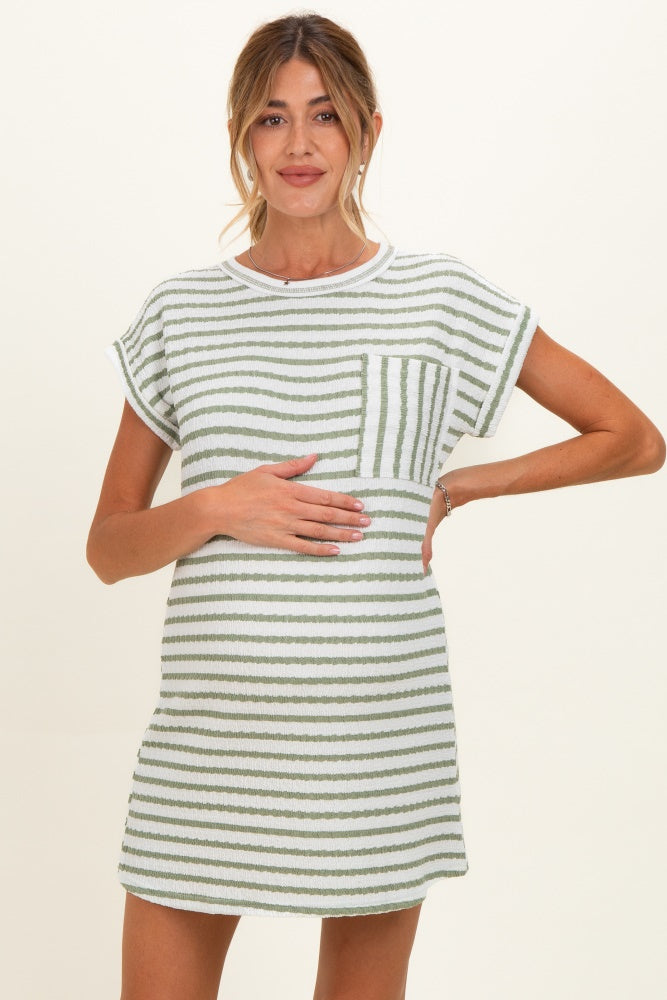 woman wearing a striped green and white maternity dress, gently holding her baby bump