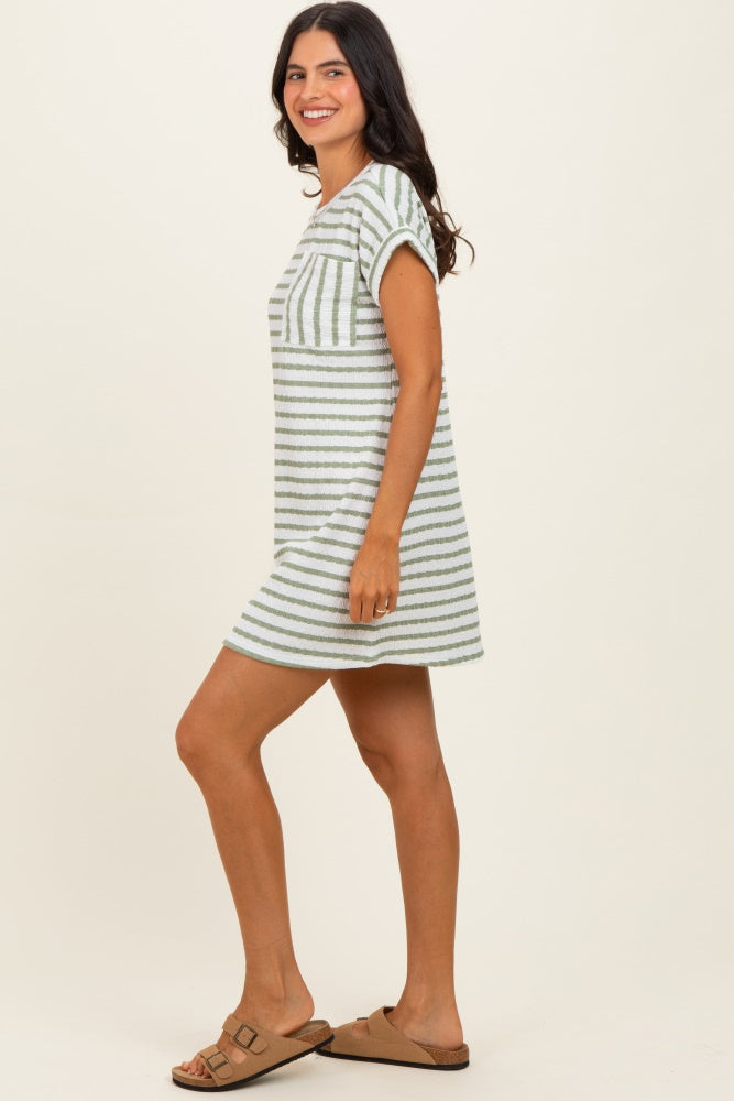 woman wearing a striped short sleeve casual dress in light green and white, standing sideways, paired with brown sandals