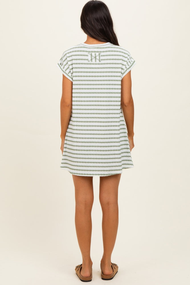 woman wearing a green and white striped short sleeve dress with a relaxed fit and a back logo detail