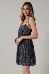woman wearing a navy floral print mini dress with adjustable straps and a smocked bodice