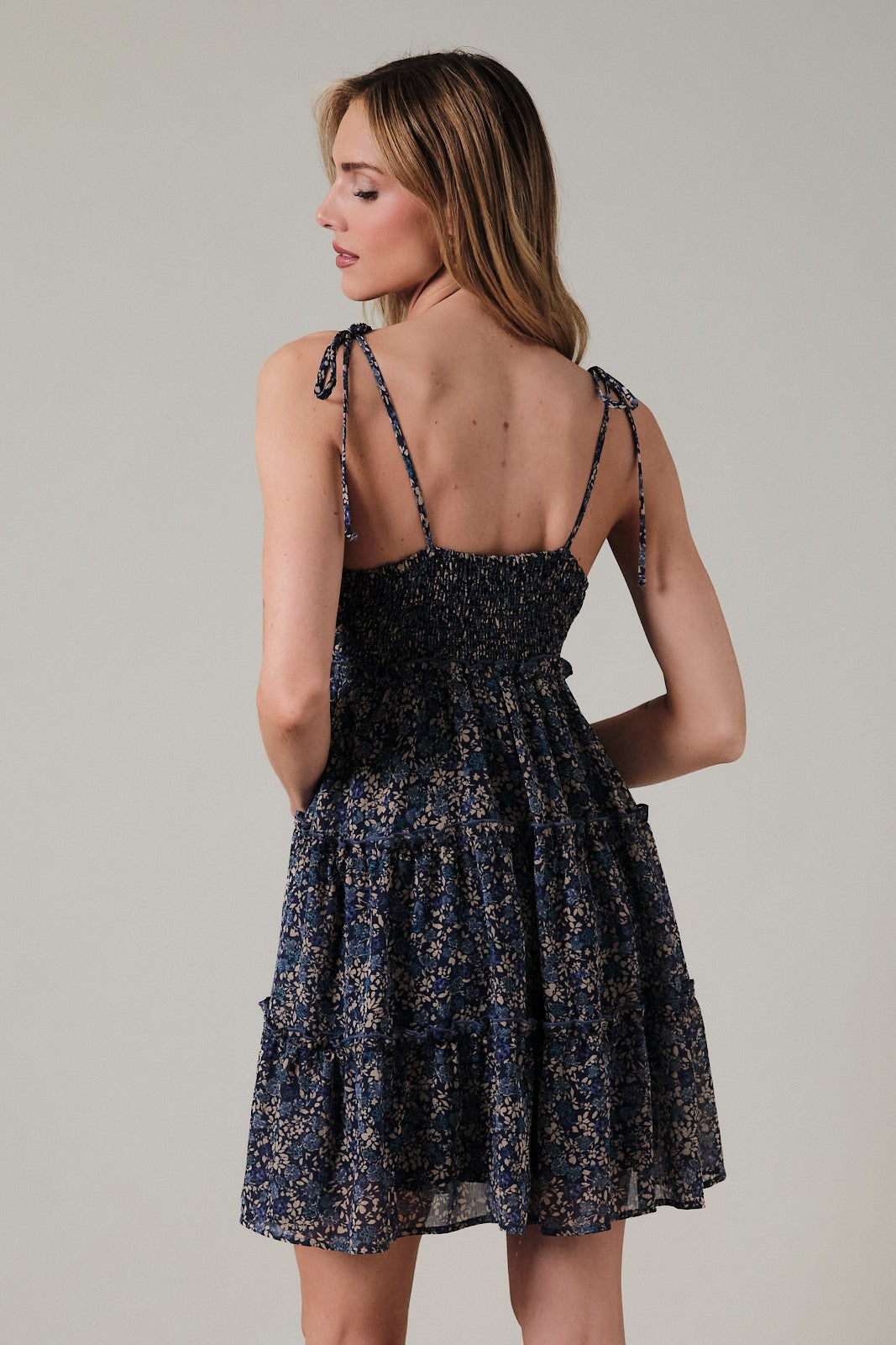 woman wearing a navy floral tiered sundress with adjustable tie straps and a smocked bodice