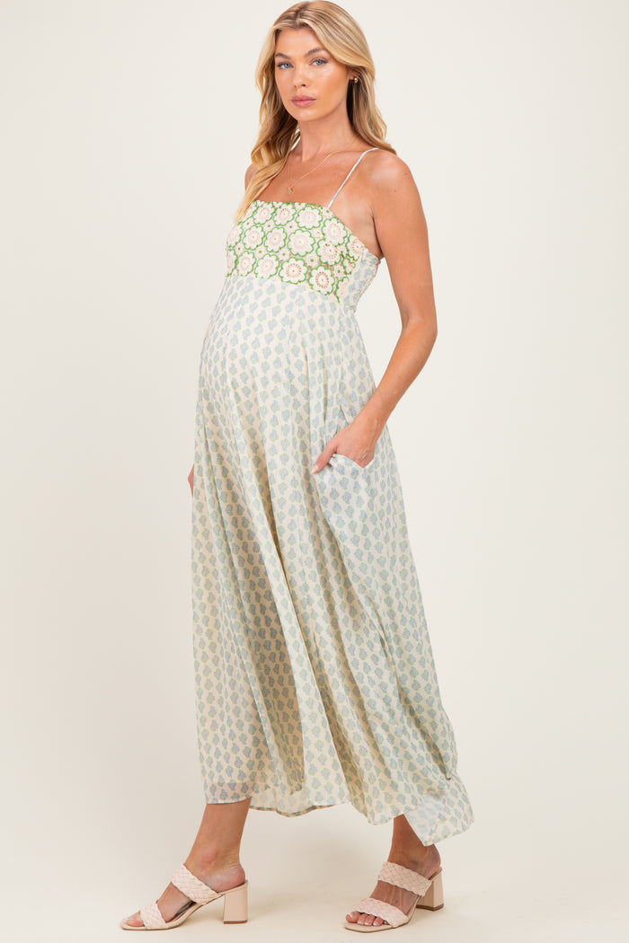 woman wearing a midi maternity dress with a floral pattern and pockets, showcasing her baby bump