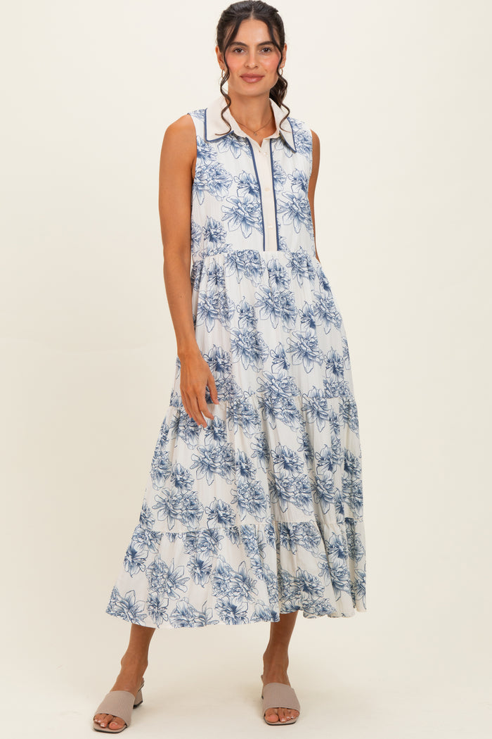 woman wearing a sleeveless white maxi dress with blue floral print and a collared neckline