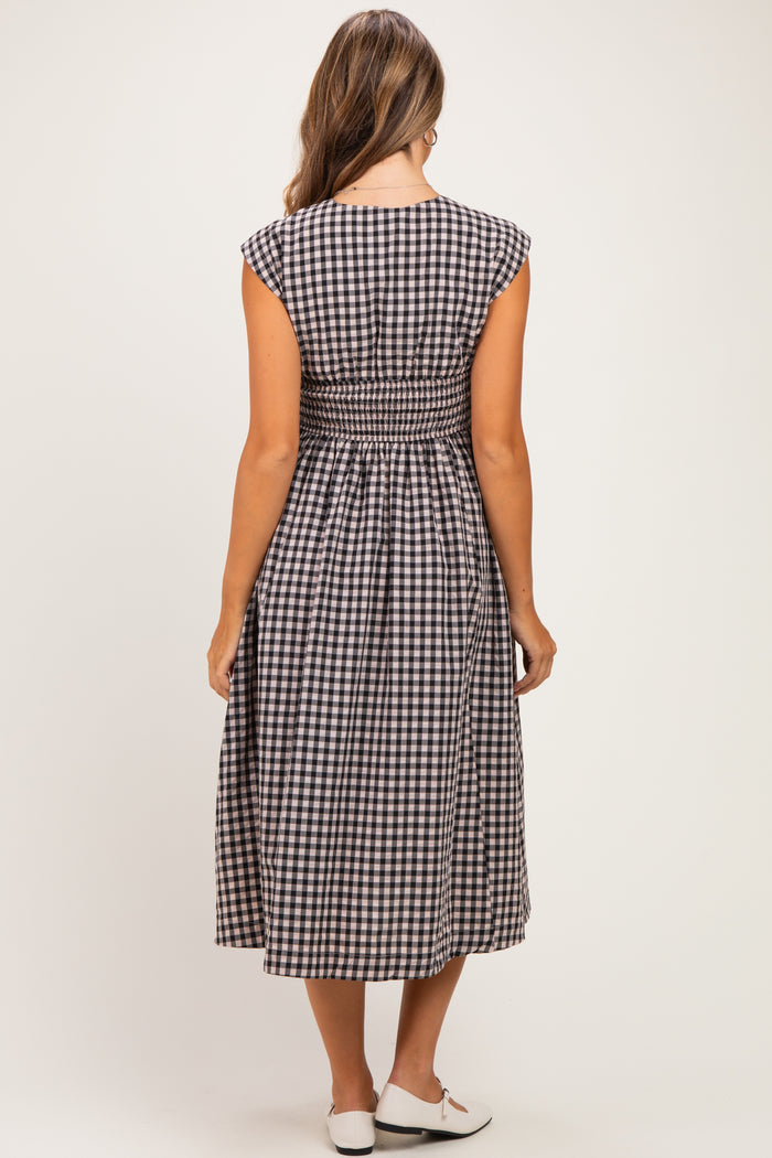 woman wearing a black and white gingham maternity dress with a smocked back detail
