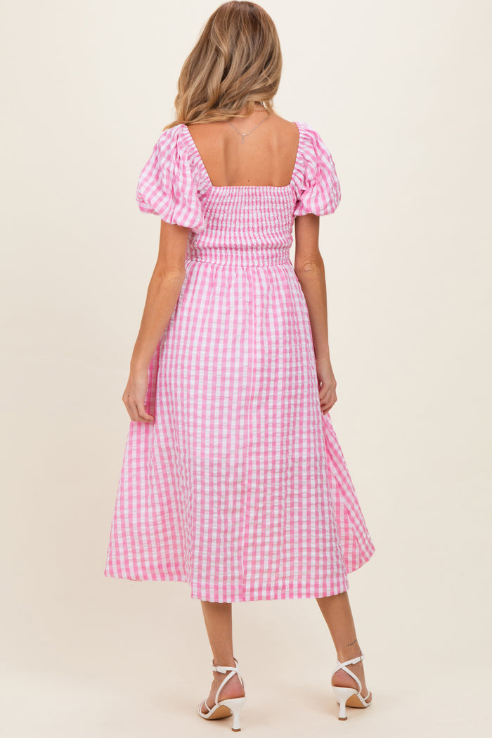 woman wearing a pink and white gingham maternity dress with puff sleeves and a smocked bodice, showing a baby bump from behind