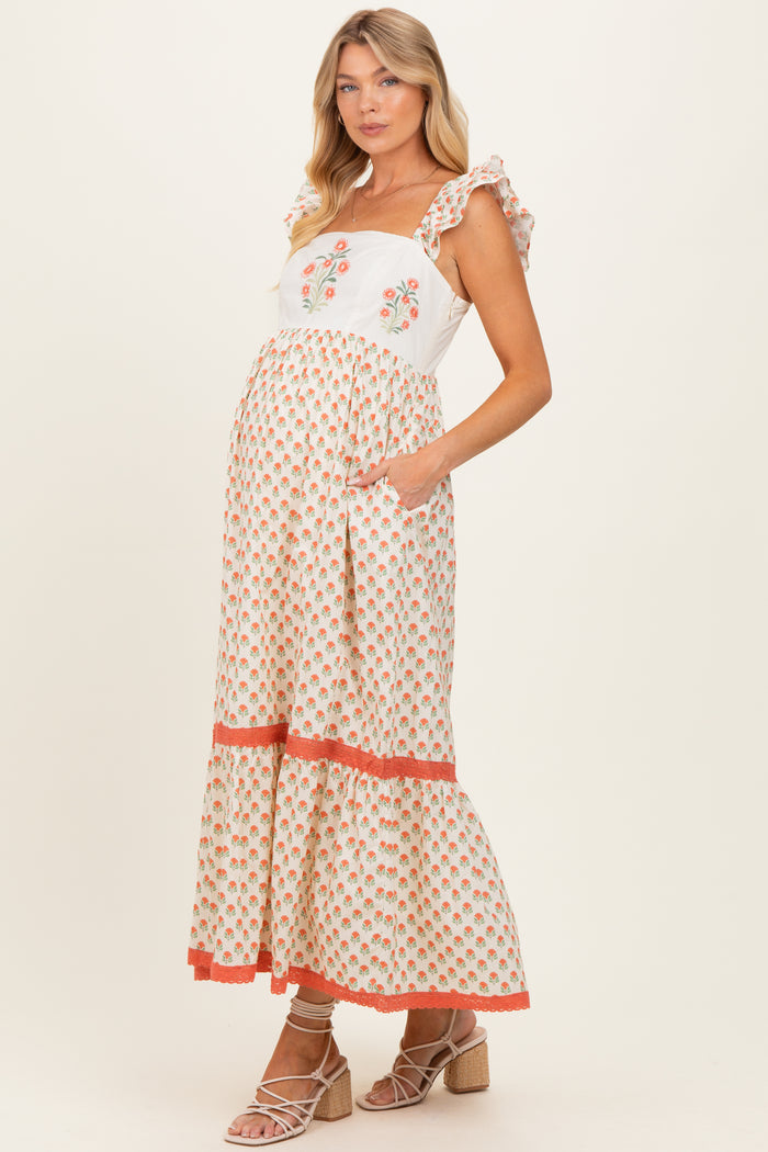 woman wearing a floral print maternity maxi dress with ruffle straps and a visible baby bump