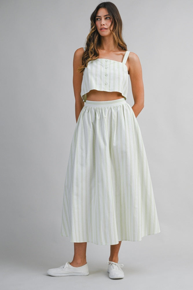 woman wearing a cropped button-up top and a long striped maxi skirt with an elastic waistband and white sneakers