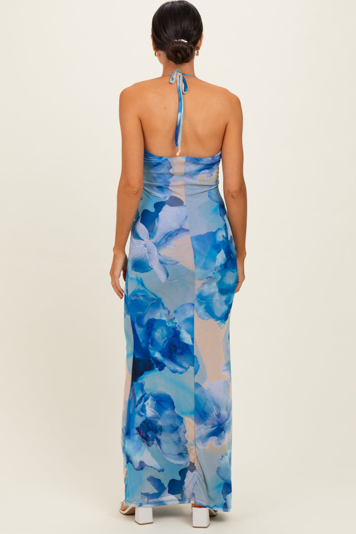 woman wearing a backless blue floral maxi dress with a halter neck and a fitted silhouette