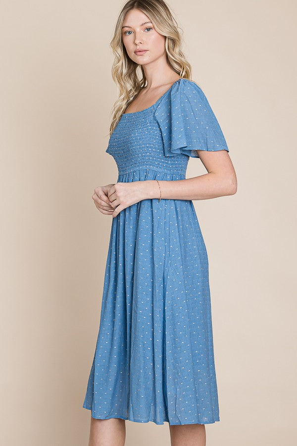 woman wearing a blue short sleeve midi dress with smocked bodice and flutter sleeves