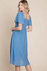 woman wearing a blue midi dress with short puff sleeves and a smocked back detail