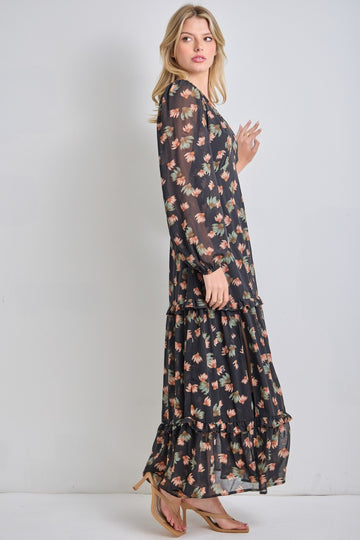 woman wearing a black floral maxi dress with long sleeves and tiered ruffles, posing sideways