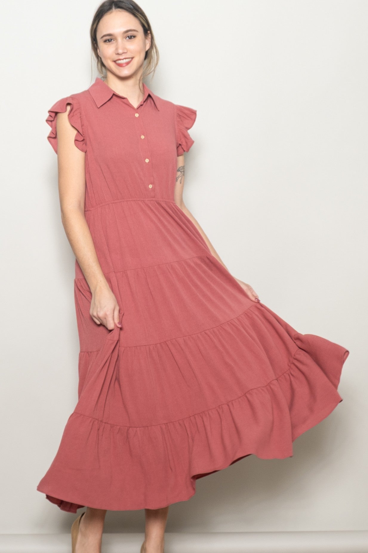 woman wearing a dusty rose tiered midi dress with ruffled sleeves and button-down placket