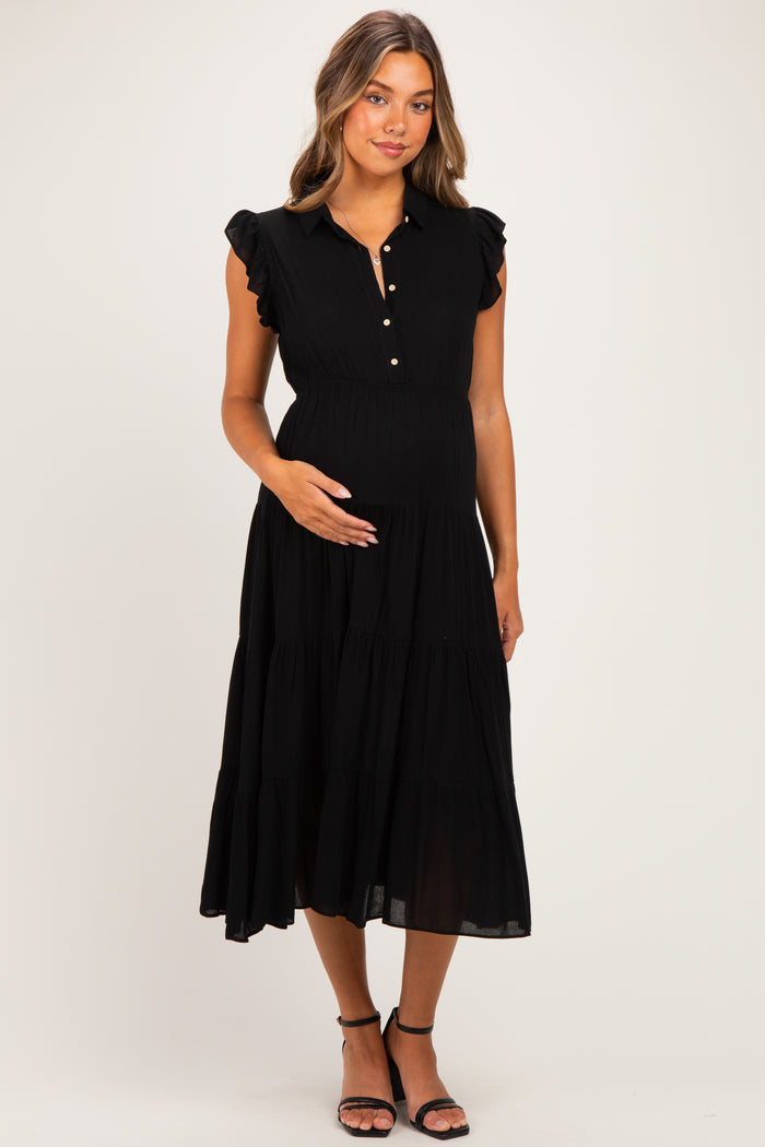 woman wearing a black maternity dress with ruffled sleeves and a button-down front, cradling her baby bump