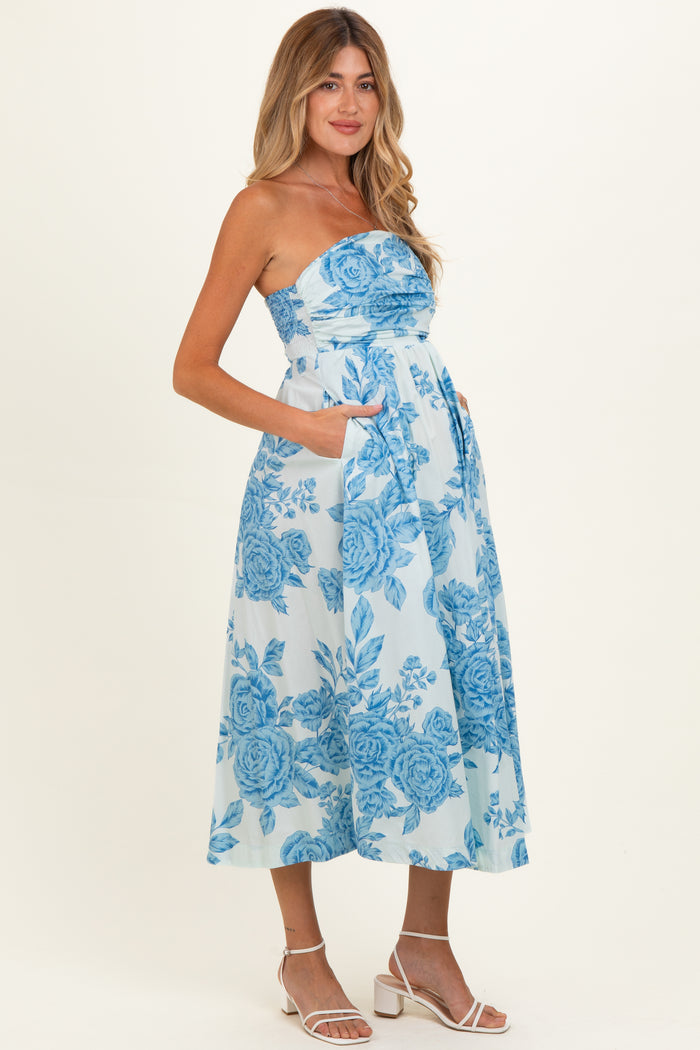 woman wearing a blue floral strapless maternity dress with pockets, showcasing her baby bump