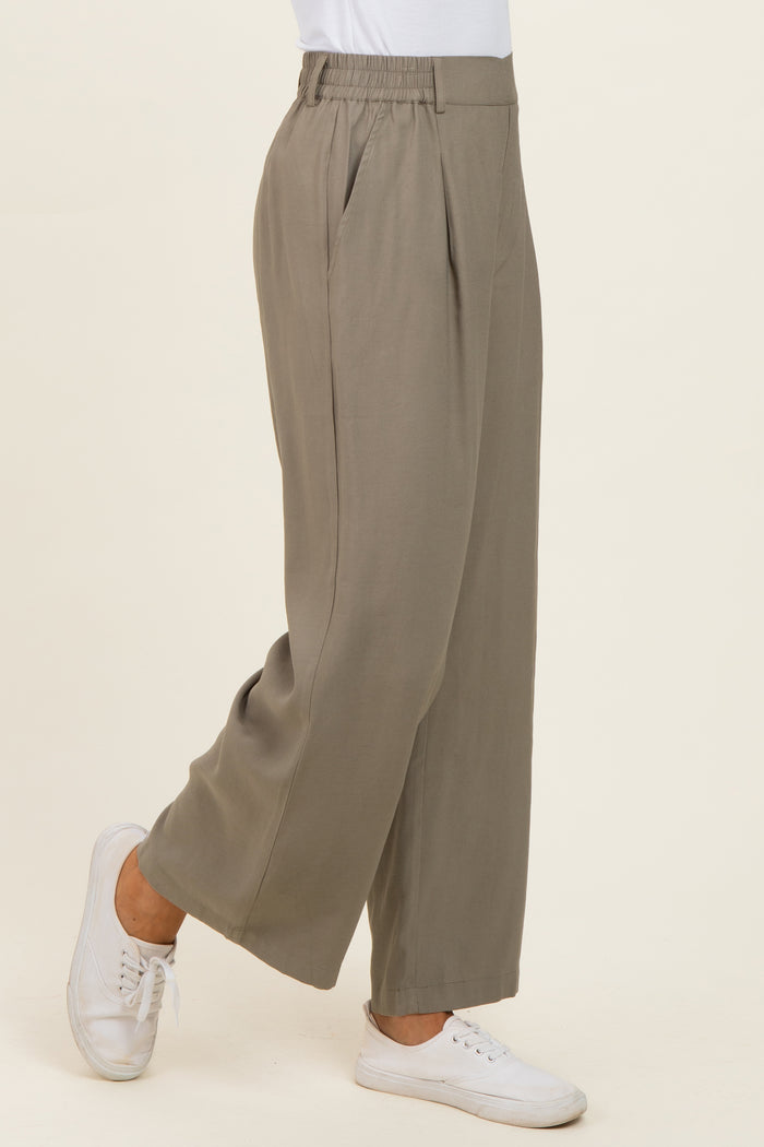 woman wearing loose-fitting light gray wide-leg trousers with an elastic waistband and side pockets