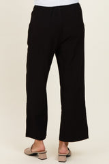 woman wearing black wide-leg pants, viewed from the back, paired with light sandals