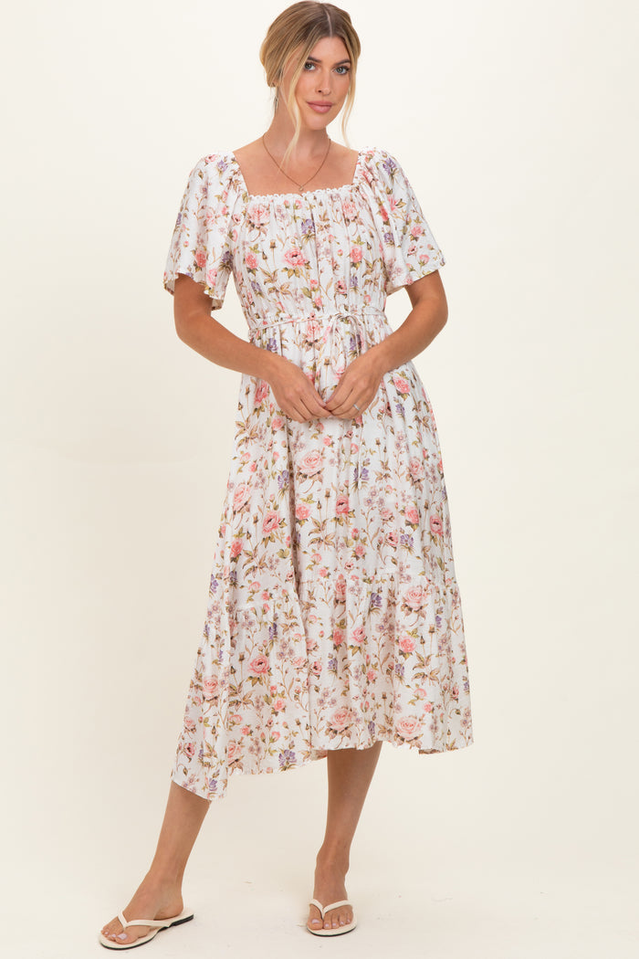 woman wearing a floral midi dress with puff sleeves and a smocked bodice, standing against a plain background