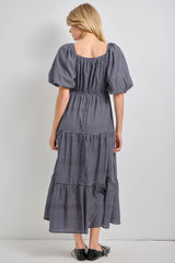 woman wearing a navy and white checked maxi dress with puff sleeves and tiered skirt, shown from the back