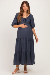 woman wearing a navy blue maternity maxi dress with short sleeves and tiered skirt, holding her baby bump