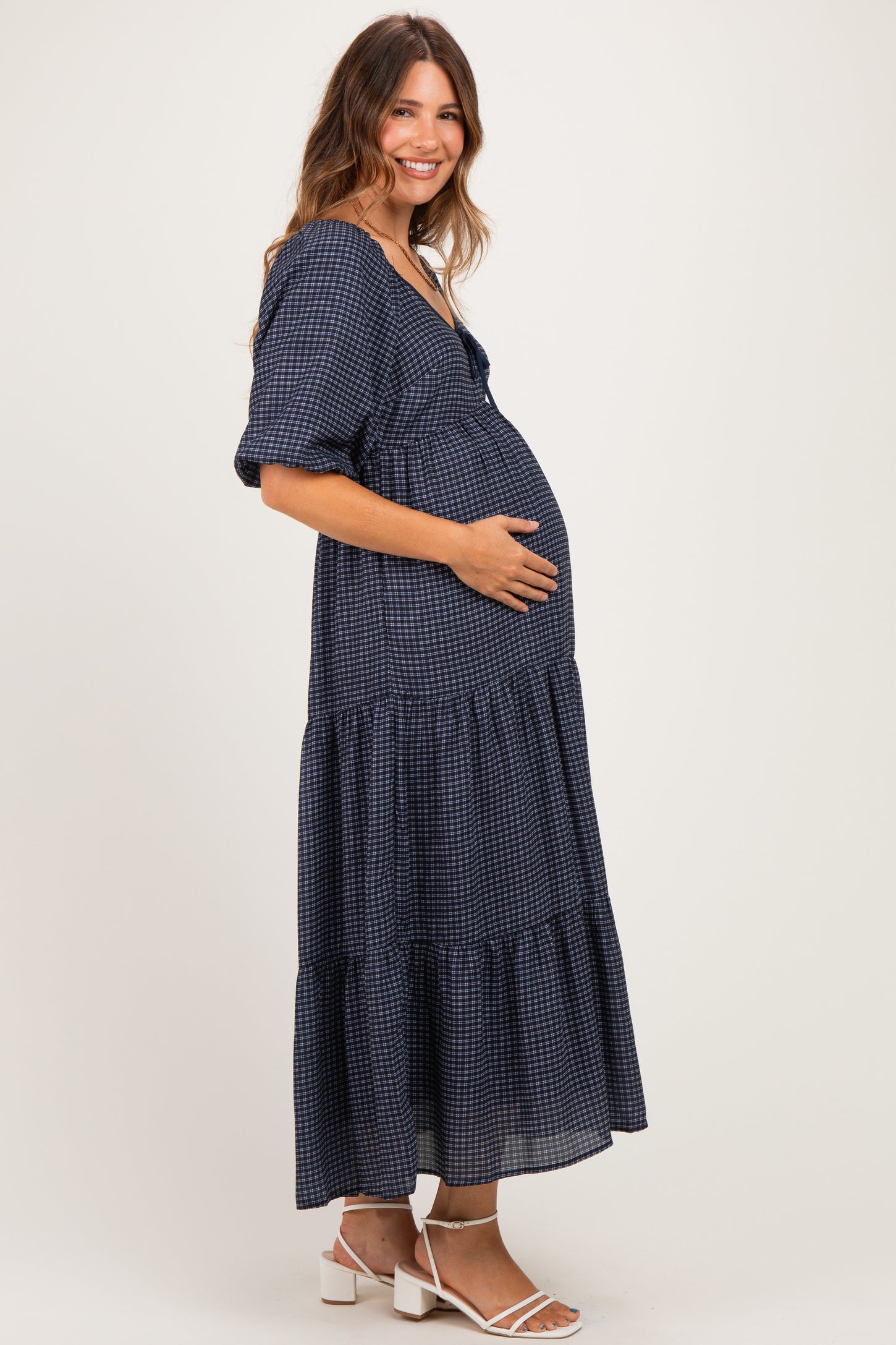 woman wearing a navy checkered maternity dress with tiered skirt and baby bump visible