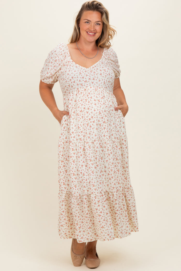 woman wearing a floral maternity plus maxi dress with short puff sleeves and side pockets, displaying a baby bump