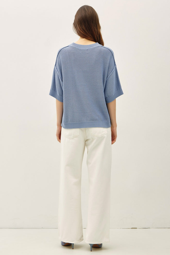 woman wearing a light blue oversized knit sweater with wide sleeves and cream-colored wide-leg pants