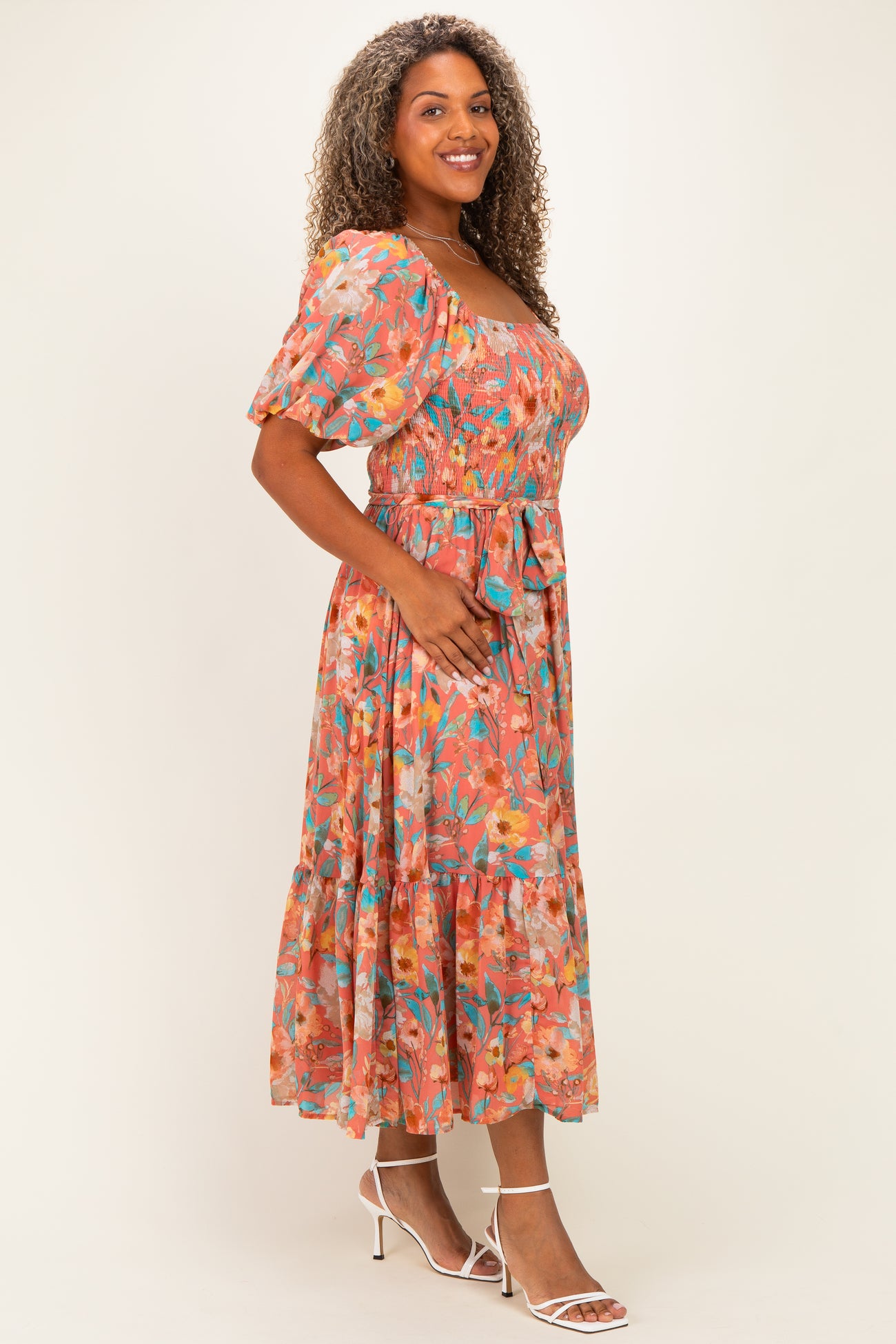 woman wearing a colorful floral plus size midi dress with puff sleeves and a cinched waist, smiling